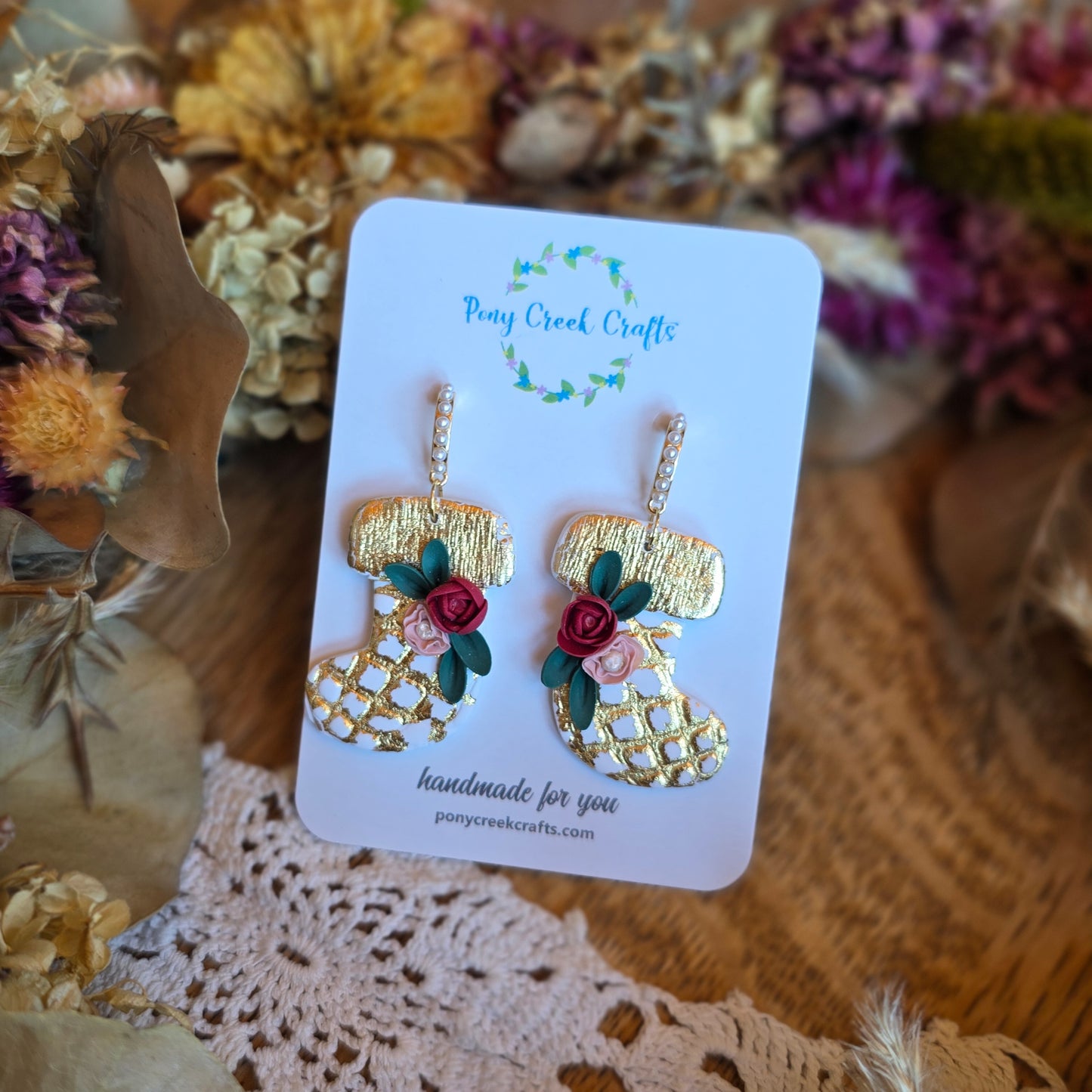 White and gold stocking shaped earrings with floral accents