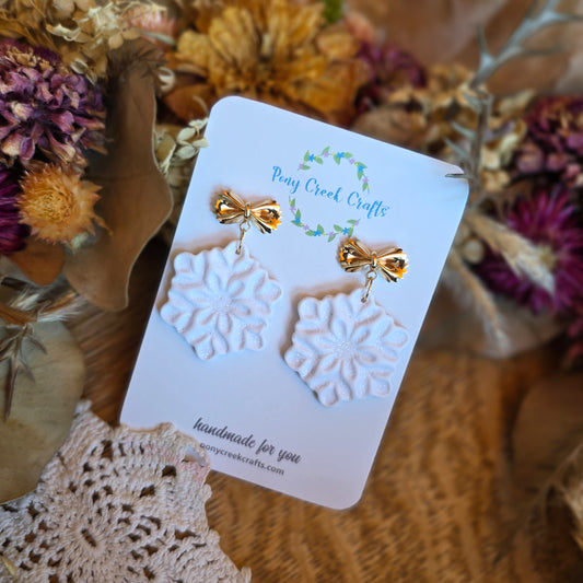 Shimmering white snowflake earrings with gold accent bow findings