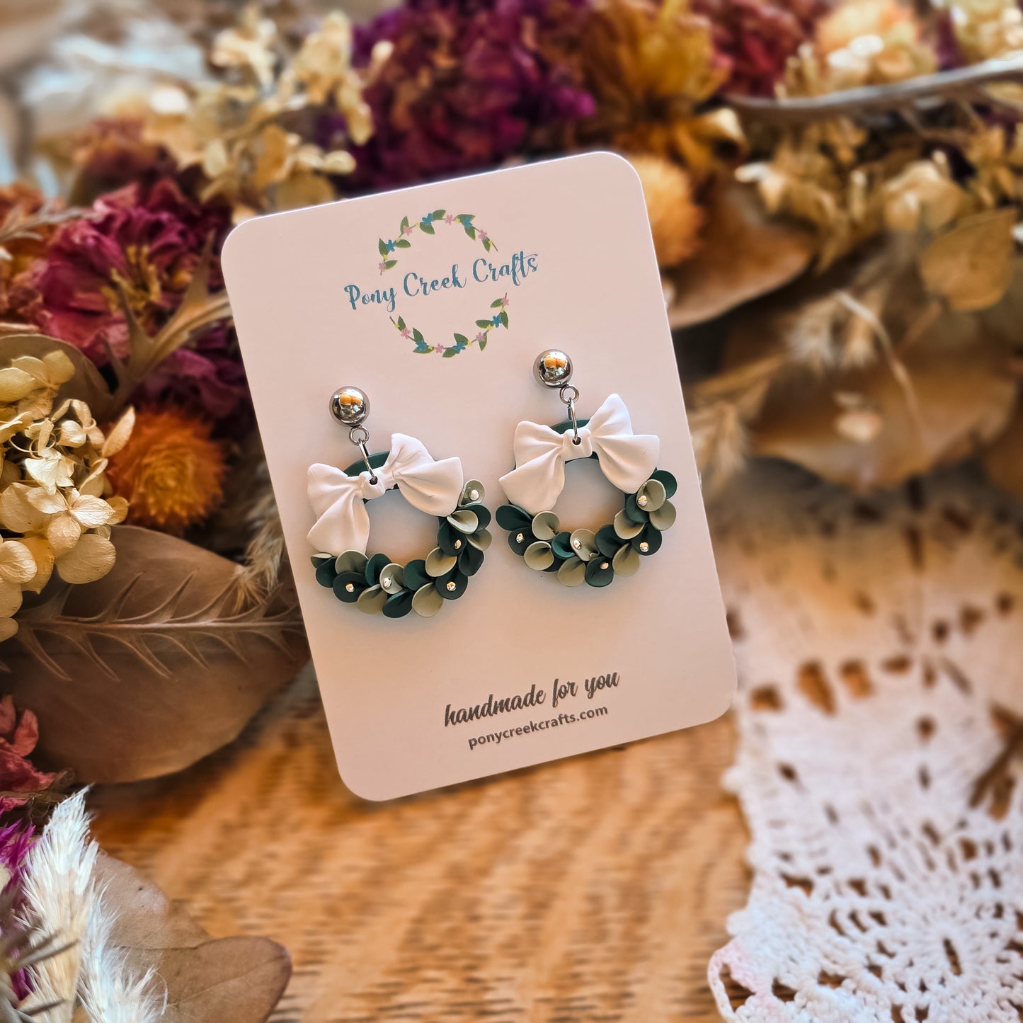 Winter wreath in greens with white bow and silver ball accents
